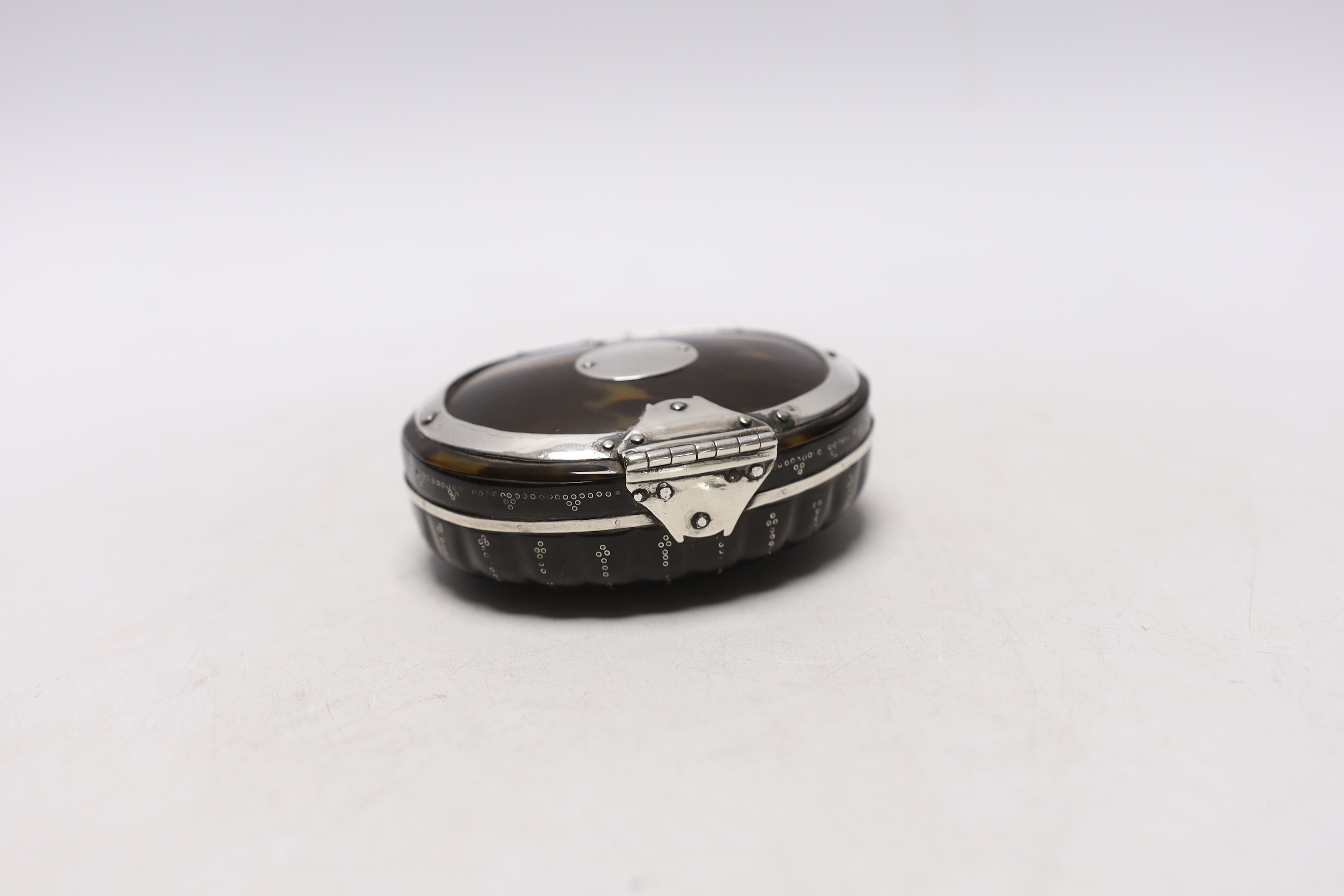 An early 19th century unmarked white metal mounted oval tortoiseshell snuff box, with fluted base, 92mm.